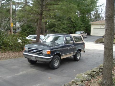 1991 Ford Bronco - A 1991 Ford Bronco is parked in a driveway with a second vehicle and a house in the background.