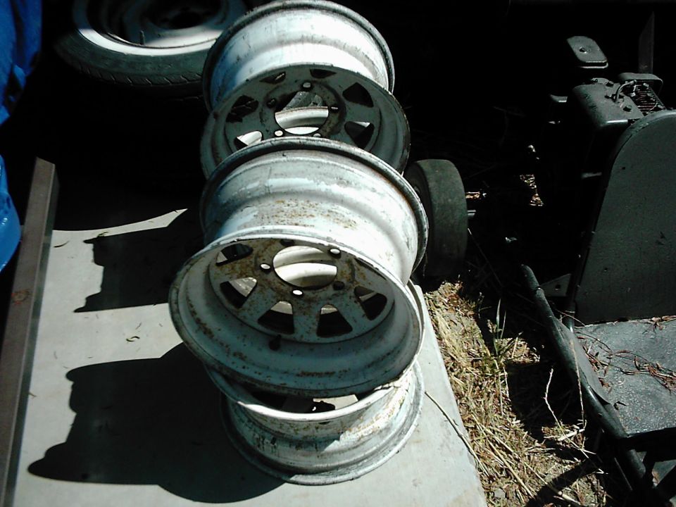 stack of four old, weathered rims piled on top of each other