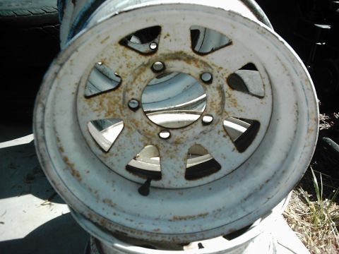 1978 Ford Bronco - A close-up view of a white steel wheel, showing signs of rust and wear.