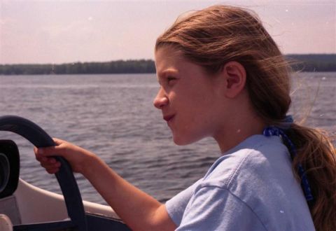 1991 Ford Bronco - Girl at the helm of a boat, navigating the water under a hazy sky.