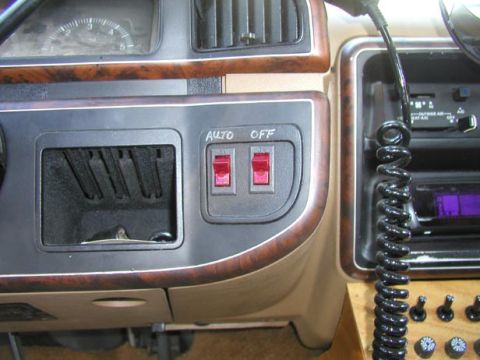 1988 Ford Bronco - Interior dash detail showing two red-lit rocker switches labeled with hand-lettered "AUTO" and "OFF" tape on a brown bezel below the cubby…