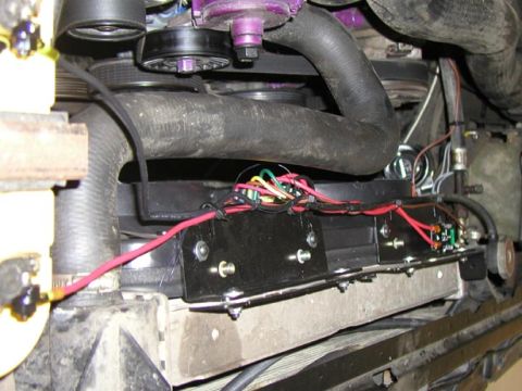 1988 Ford Bronco - Completed electric cooling fan installation viewed from above the radiator, with the black fan assembly's flat top rail bolted in place and…