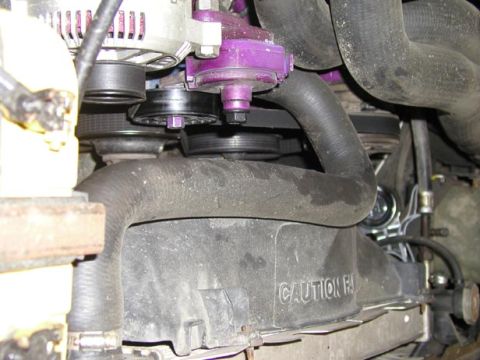 1988 Ford Bronco - Tight engine-bay shot down the front of a V8 showing the black plastic engine-driven fan shroud molded with a raised "CAUTION FAN" warning,…