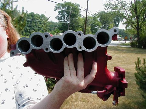 1997 Ford Taurus - A red intake manifold is held up for display, with a person's arm and hand visible.