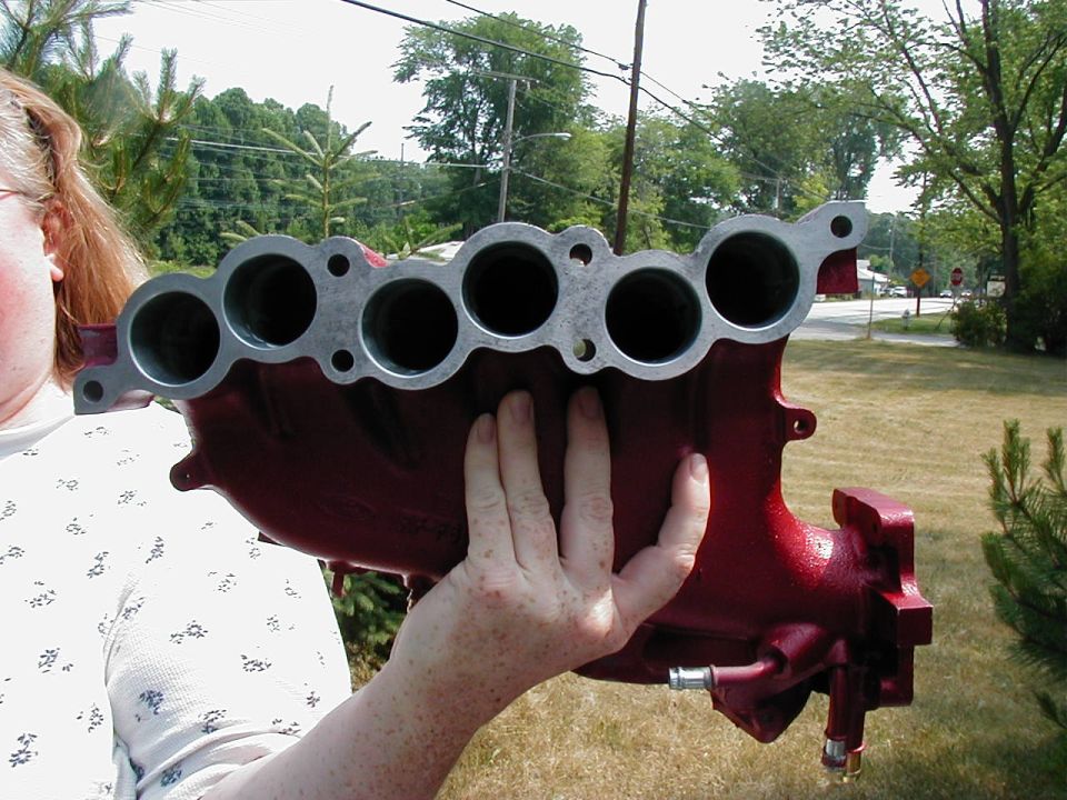 Red intake manifold held by a person