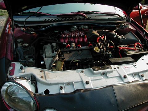 1997 Ford Taurus - The engine bay of a 1997 Ford Taurus features red accents on the intake manifold and spark plug wires.