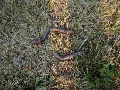 1997 Ford Taurus - Two metal pipes, possibly exhaust or fuel lines, are shown on a grassy surface.