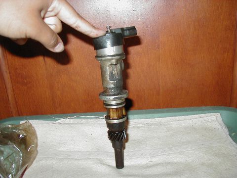 1997 Ford Taurus - A car distributor part is shown, with a finger pointing to the top electrical connector.