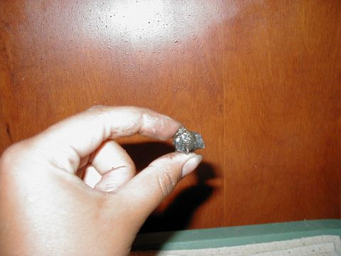 1997 Ford Taurus - A hand holds a small, metallic object against a wooden background.