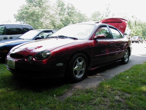 1997 Ford Taurus - Red 1997 Ford Taurus sedan with its trunk open, parked outdoors.