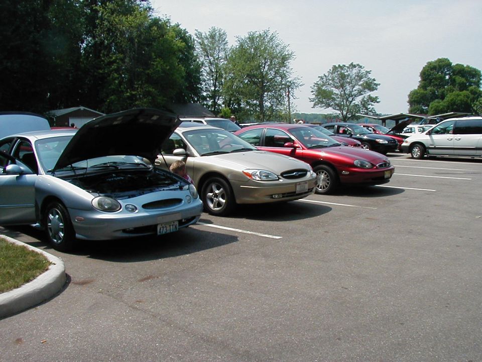 Silver 1997 Ford Taurus with hood open, parked in a lot