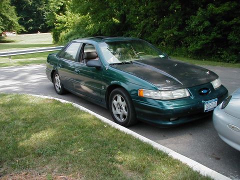 1997 Ford Taurus - Green 1997 Ford Taurus sedan with a black hood, parked on the side of the road.