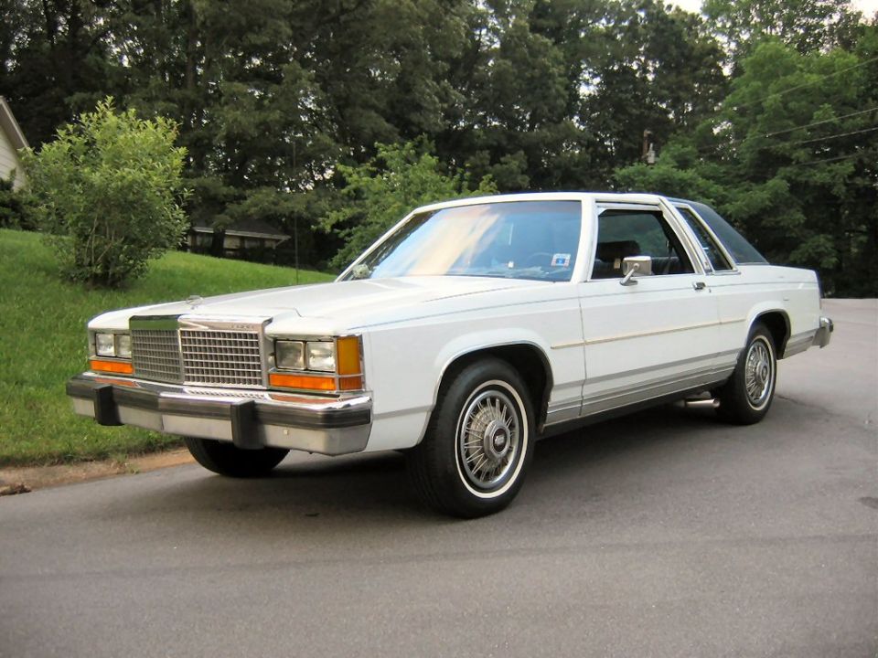 White 1980s Ford LTD Crown Victoria coupe parked on a residential street