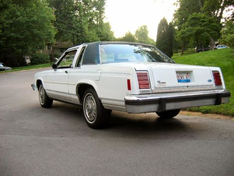 1985 Ford Crown Victoria LTD - This white two-door sedan with a green roof displays a license plate indicating the year 1987.