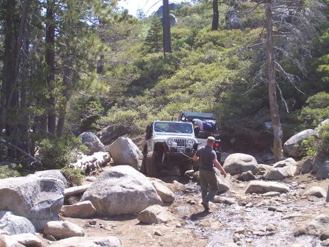 1998 Ford Ranger - Two Jeeps navigate a challenging, rocky trail through a dense forest on a sunny day.