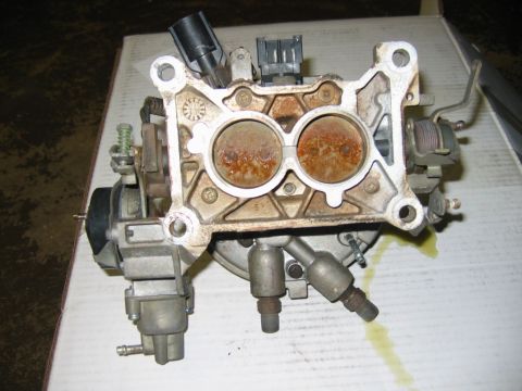 1985 Ford Crown Victoria LTD - This is a carburetor, a part of a vehicle's fuel system, with visible rust in its intake ports.