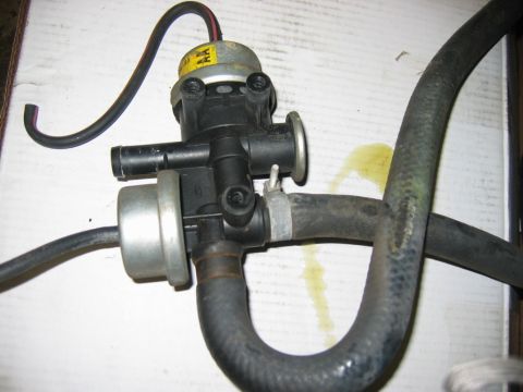 1985 Ford Crown Victoria LTD - A close-up view of a vehicle vacuum actuator and attached hoses, with a yellow fluid stain visible on the surface.