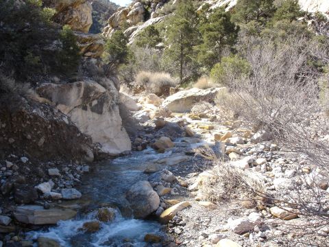 1996 Ford Bronco - A dry creek bed winds through a rocky, mountainous landscape with sparse vegetation.