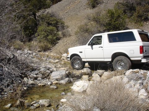 1996 Ford Bronco - White 1996 Ford Bronco driving over rocks in a dry creek bed.