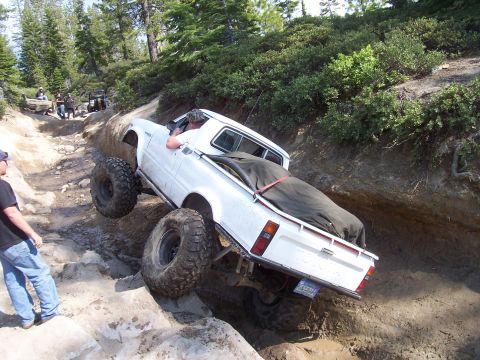 1998 Ford Ranger - A modified pickup truck is shown tackling a challenging off-road obstacle on a dirt path.