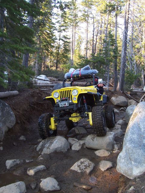 1998 Ford Ranger - A yellow Jeep is shown off-roading through a rocky, muddy trail surrounded by trees.