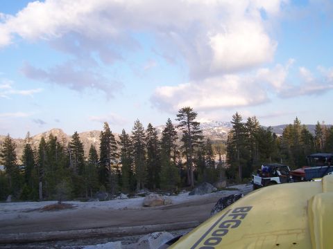 1998 Ford Ranger - A yellow vehicle part with BFGoodrich text is in the foreground, with several off-road vehicles parked on a dirt road in a mountainous, for…