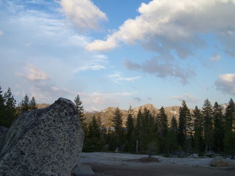 1998 Ford Ranger - Mountain landscape with pine trees and a large rock in the foreground under a partly cloudy sky.