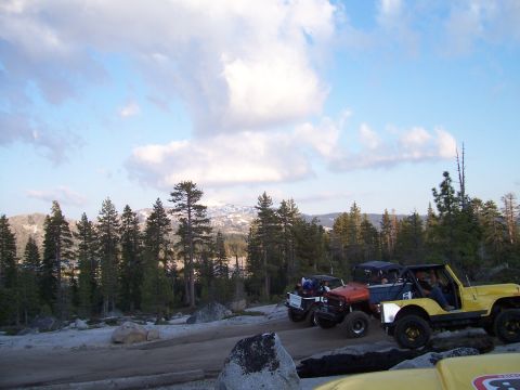 1998 Ford Ranger - Several off-road vehicles navigate a rocky trail under a cloudy sky, with a mountainous landscape in the distance.