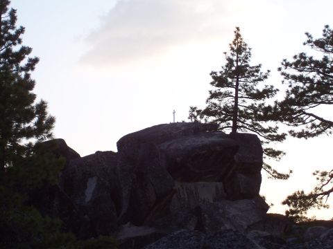 1998 Ford Ranger - A cross stands atop a rocky outcrop surrounded by trees under a hazy sky.