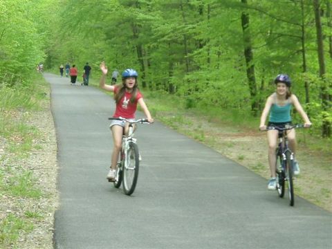 1966 Land Rover Discovery - Two young girls enjoy a bike ride on a sunny day through a tree-lined park trail.