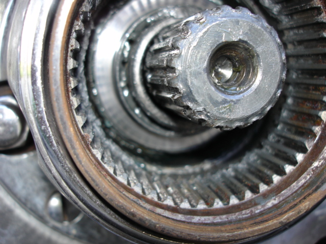 Close-up of a worn vehicle hub assembly with visible gear teeth and a threaded center