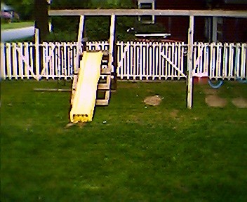 1966 Land Rover Discovery - A backyard scene with a swing set and a white picket fence.