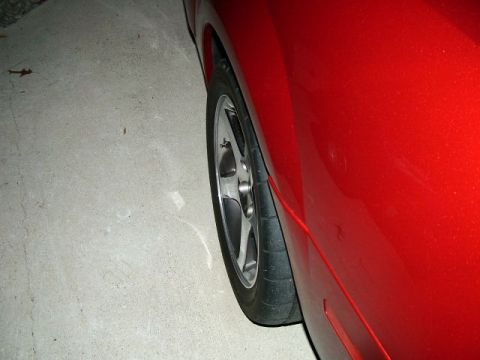 2003 Ford Mustang - Close-up view of the rear wheel and fender of a red 2003 Ford Mustang.