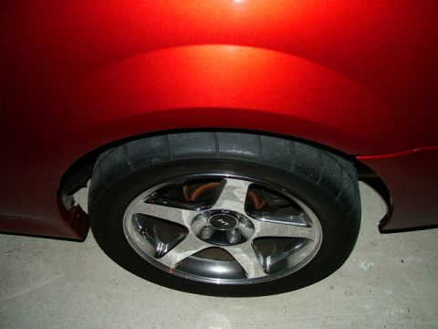 2003 Ford Mustang - Close-up of the rear wheel and fender of a red 2003 Ford Mustang Cobra.
