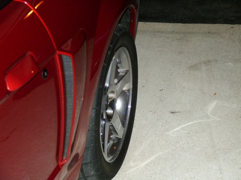 2003 Ford Mustang - Close-up of a red car's side panel and wheel, showing a vent detail.