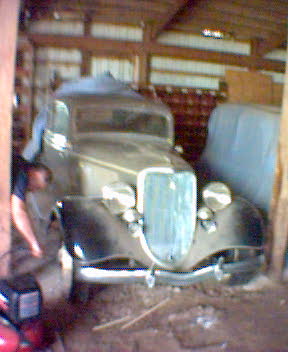 1994 Ford Bronco - A vintage Ford truck sits in a barn, partially obscured by a tarp-covered vehicle.