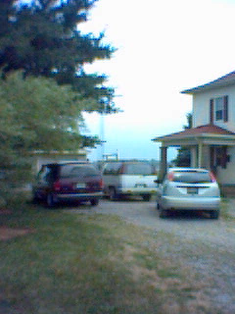 1994 Ford Bronco - A silver car and two vans are parked in a gravel driveway next to a house.