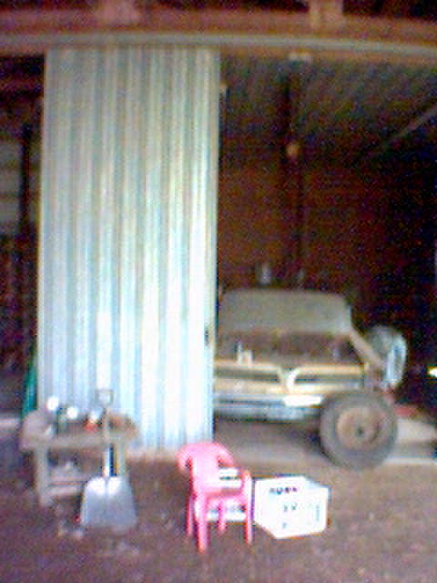 1994 Ford Bronco - This weathered truck sits in a garage, its front grille partially obscured by a large corrugated metal partition.