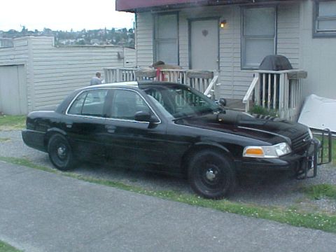 1999 Ford Crown Victoria - A black 1999 Ford Crown Victoria police car is parked in front of a building.