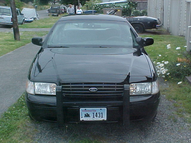 Black Ford Crown Victoria police car with push bar, front view. License plate reads 1431