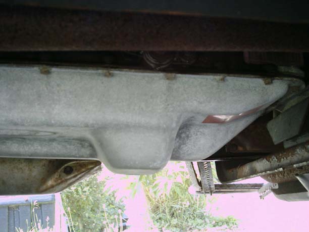 Underside view of a transmission pan with some rust on surrounding components
