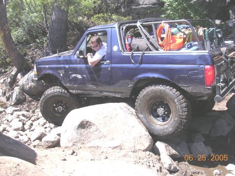 1994 Ford Bronco - A blue Ford Bronco is shown navigating a rocky trail with its tires on large boulders.