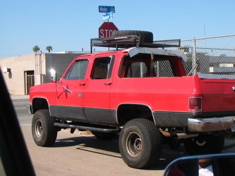 1986 Ford Bronco - This red SUV, likely from the 1970s or 1980s, is equipped with a roof rack and spare tire.