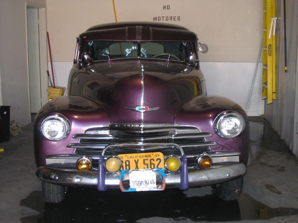 Front view of a purple vintage car with a chrome grille and a California license plate that reads '38 X 562'