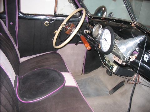 1986 Ford Bronco - The interior of a car shows custom upholstery and a dashboard with a clock and radio.