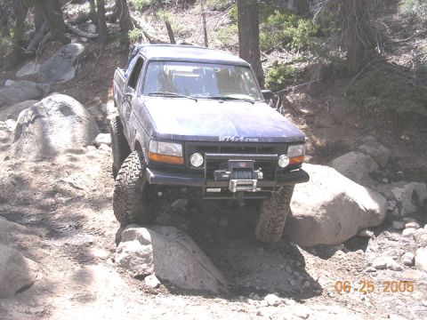 1994 Ford Bronco - A dark blue 1992 Ford Bronco is shown off-roading on a rocky trail.