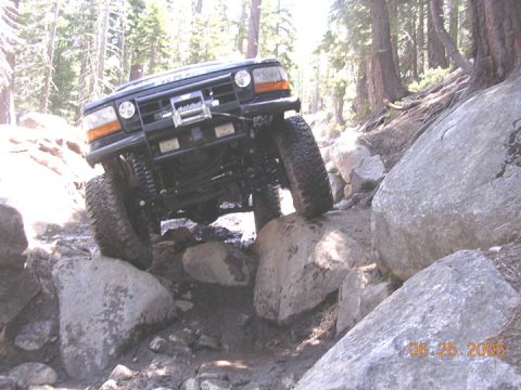 1994 Ford Bronco - This 1994 Ford Bronco is shown tackling a challenging off-road course with significant rock obstacles.