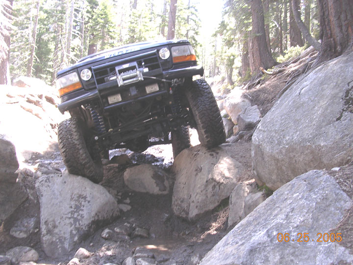 1994 Ford Bronco navigating a steep, rocky trail with large boulders