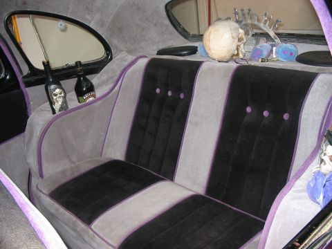1986 Ford Bronco - The interior of a car shows custom seats and decorative items, including a skull and bottles.