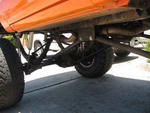 1986 Ford Bronco - Undercarriage view of an orange SUV, revealing its suspension and exhaust system.